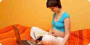 la mujer Embarazada con el libro y el ordenador portatil